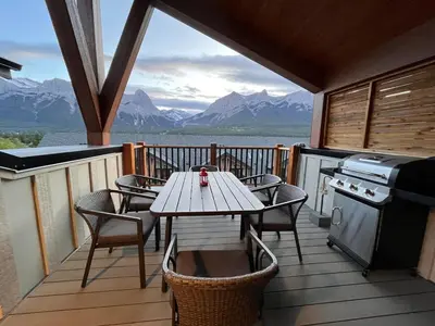 a table and chairs on a balcony with a table and a stove at Top FL 2BR 2BA Hot Tubs phenomenal mountain views in Canmore