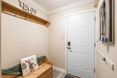 a room with a white door and a wooden bench at Gondola Heights by Outpost Whistler in Whistler