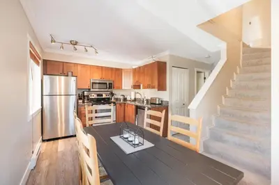a kitchen and dining room with a table and a staircase at Gondola Heights by Outpost Whistler in Whistler
