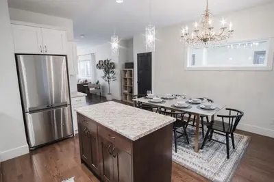 a kitchen with a dining table and a refrigerator at DOWNTOWN KINGBED 4Br FIREPLACE BIKELANE in Edmonton