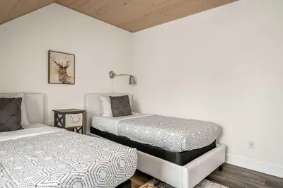 two beds in a room with white walls at Radiant Retreat -Spacious Home - Heart of Radium! in Radium Hot Springs