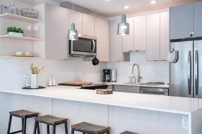 a kitchen with white cabinets and a refrigerator and stools at Alpenstoke in Revelstoke