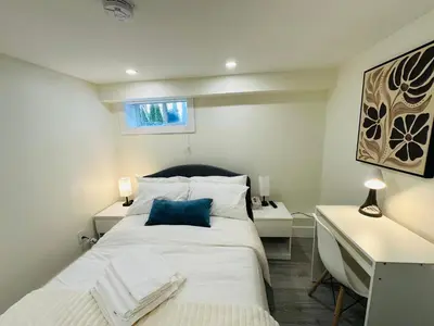 a bedroom with a large white bed and a desk at Quiet Basement Suite Steps from Quilchena Park in Vancouver in Vancouver