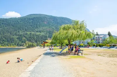 a group of people sitting on a beach at 2 Bedroom with Lake and Mtn Views in Harrison Hot Springs