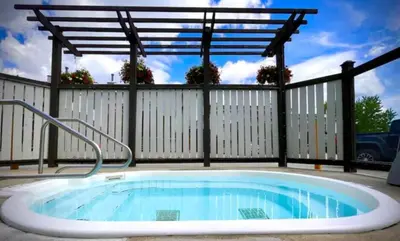 a hot tub in a backyard with a fence at Mountain Edge Resort Inn by StayIn in Kimberley
