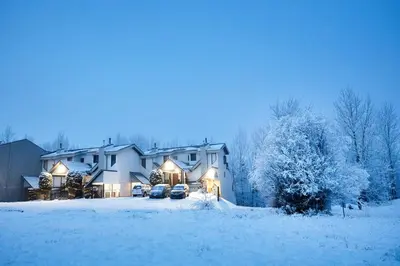 a house in the snow with cars parked in the driveway at Mountain Edge Resort Inn by StayIn in Kimberley
