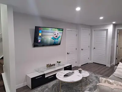 a living room with a flat screen tv on a wall at Cozy 2 Bedroom Walkout Basement in Calgary
