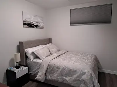 a bedroom with a bed and a nightstand with a bed sidx sidx sidx sidx at Cozy 2 Bedroom Walkout Basement in Calgary