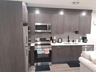 a kitchen with wooden cabinets and a stove top oven at Cozy 2 Bedroom Walkout Basement in Calgary