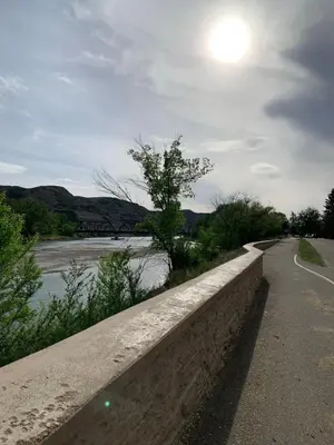a road next to a river with the sun in the sky at Spacious Drumheller-RetreatMuseum & Golf in Drumheller