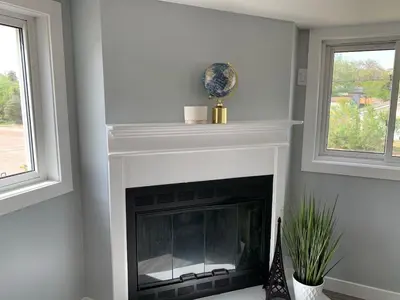 a fireplace in a living room with two windows at Spacious Drumheller-RetreatMuseum & Golf in Drumheller