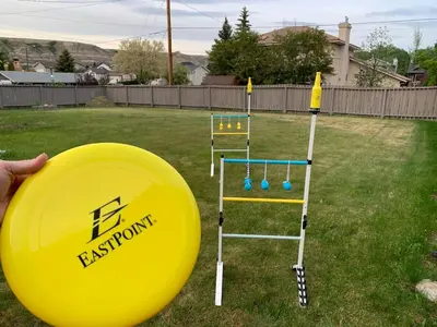 a person holding a yellow frisbee in a yard at Spacious Drumheller-RetreatMuseum & Golf in Drumheller