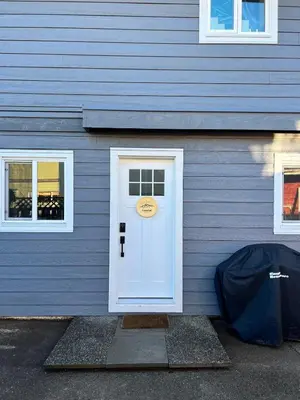 a blue house with a white door and two windows at Coastal Suite - Harbourview in Ucluelet in Ucluelet
