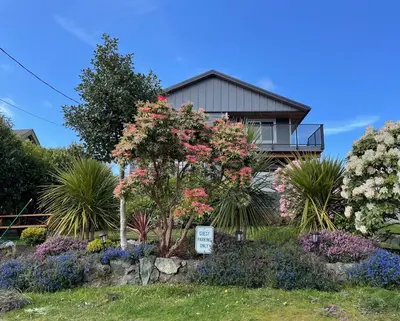 a house with a sign in front of a garden at Coastal Suite - Harbourview in Ucluelet in Ucluelet