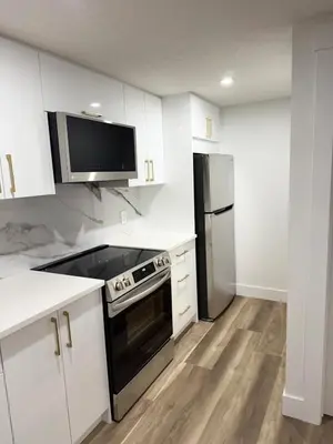 a kitchen with white cabinets and a black oven and refrigerator at Charming Basement Suite in Edmonton