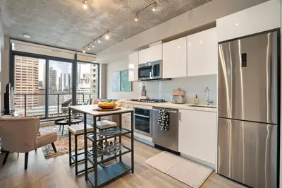 a kitchen with a refrigerator and a table with a table at Stylish Condo with Exclusive Rooftop Pool in Calgary