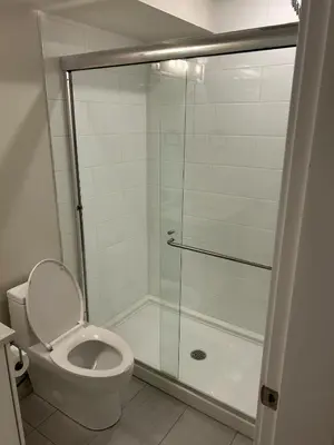 a bathroom with a toilet and a glass shower at Spacious one Bedroom Suite Right in Downtown ! in Maple Ridge District Municipality