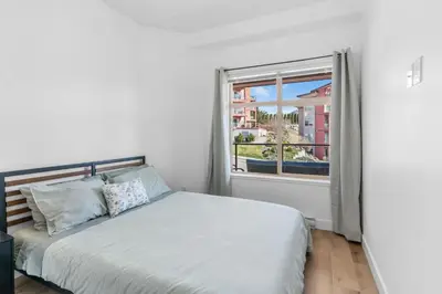a white bedroom with a bed and a window at Luxury Lake View Condo in West Kelowna, 5 Star Resort with Pool, Hot Tub and Gym in West Kelowna
