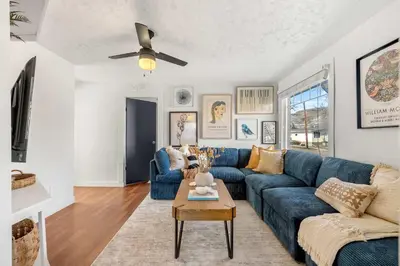 a living room with a blue couch and a ceiling fan at Bluebird 3 Bedroom Home in the Heart of Drumheller in Drumheller