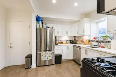 a kitchen with white cabinets and a stainless steel refrigerator at Beautiful Vancouver Cedar Cottage House in Vancouver