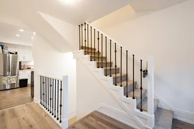 a white staircase with black railings in a kitchen at Beautiful Vancouver Cedar Cottage House in Vancouver