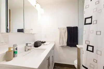 a white bathroom with a sink and a mirror at Beautiful Vancouver Cedar Cottage House in Vancouver