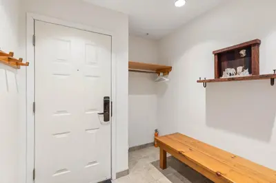 a hallway with a white door and a wooden bench at Foxglove by Whistler Premier in Whistler