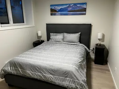 a bedroom with a large bed with two lamps at The Oasis-A New 1 bed suite in Livingston Calgary close to the Airport in Calgary