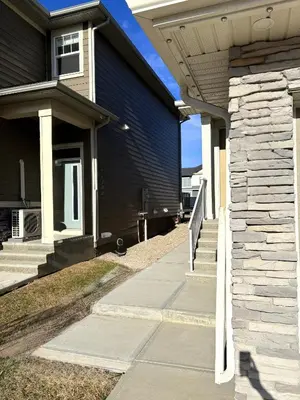a house with a walkway next to a building at Coziest & Modern Basement Retreat East of Calgary in Chestermere