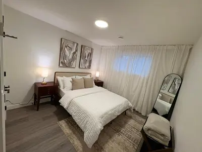 a bedroom with a bed and two night stands and a window at Coziest & Modern Basement Retreat East of Calgary in Chestermere