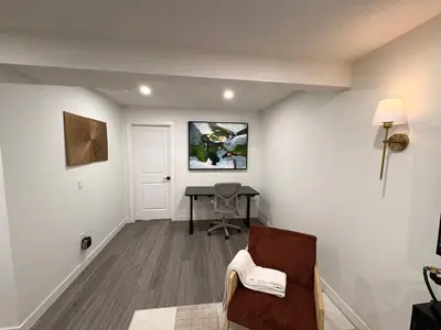 a living room with a table and a chair at Coziest & Modern Basement Retreat East of Calgary in Chestermere