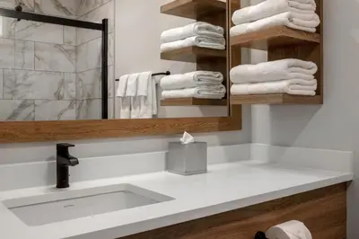 a bathroom with a sink and a mirror and towels at Canalta Cochrane in Cochrane