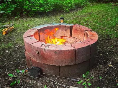 a brick fire pit sitting in the grass at Everlong Acres Belle Tent in Owlseye