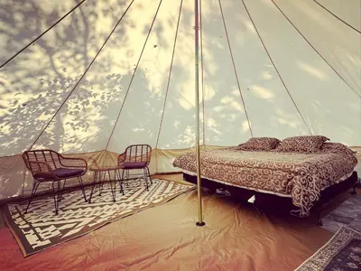 a bedroom with two chairs and a bed in a tent at Everlong Acres Belle Tent in Owlseye