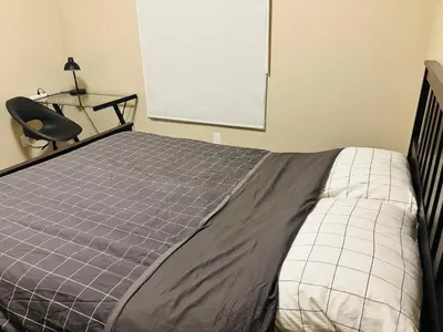 a bedroom with a bed and a black chair and a chalkboard at Main Floor 1 Bedroom Suite with Parking in Calgary