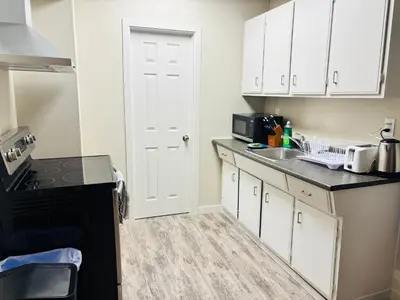 a kitchen with white cabinets and a black counter top at Main Floor 1 Bedroom Suite with Parking in Calgary