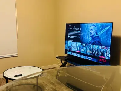 a living room with a tv and a glass table at Main Floor 1 Bedroom Suite with Parking in Calgary