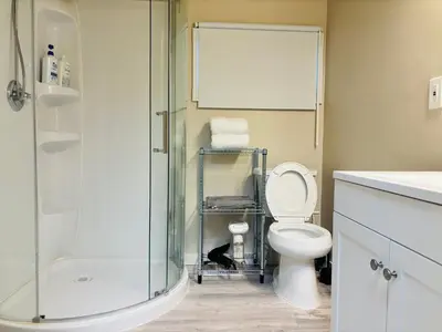 a bathroom with a toilet and a glass shower at Main Floor 1 Bedroom Suite with Parking in Calgary