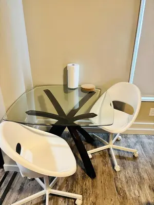 a glass table and two white chairs in a room at Upper Floor 1 Bedroom Suite with Parking in Calgary