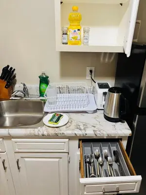 a kitchen counter with a sink and a dish drying rack at Upper Floor 1 Bedroom Suite with Parking in Calgary