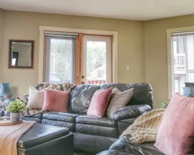 a leather couch with pillows on it in a living room at Relaxing Mountain View Condo in Beautiful Radium in Radium Hot Springs
