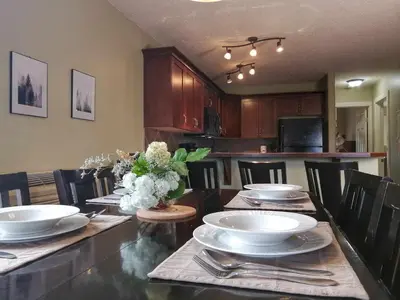 a dining room with a table with plates and flowers on it at Relaxing Mountain View Condo in Beautiful Radium in Radium Hot Springs