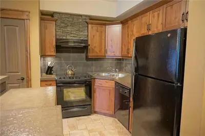 a kitchen with a black refrigerator and wooden cabinets at Mountain View Retreat in Radium Hot Springs