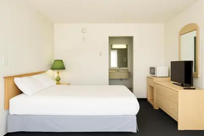 a bedroom with a white bed and a television at Silver crest lodge in Grande Prairie