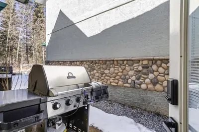 a grill in a yard next to a stone wall at 2BR 2BA Harvie Heights Townhouse retreat with views in Canmore