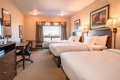 a hotel room with four beds and a desk at Canalta High River in High River