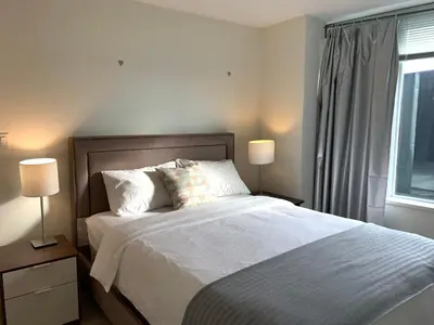 a bedroom with a bed with two lamps and a window at Amazing brand new 2bedr&2bathr in Richmond center in Richmond