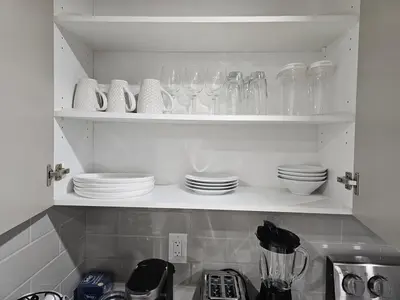 a kitchen shelf with plates and glasses on it at Brand-New Guesthouse-2bedrooms in Calgary
