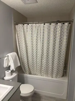 a bathroom with a toilet and a shower curtain at Spacious 2BR Suite - SW Edmonton in Edmonton