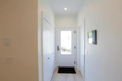 a hallway with a white door and a black rug at Aurelia Guest Suite and Sauna in Tofino